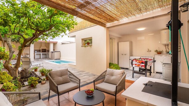 Eine Außenpatio-Terrasse mit Pool, zwei gepolsterten Stühlen, einem kleinen runden Tisch mit Obst und einem Tischfußball.