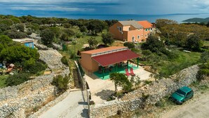 An aerial view of a property with a large house, a covered patio, and a car parked nearby.