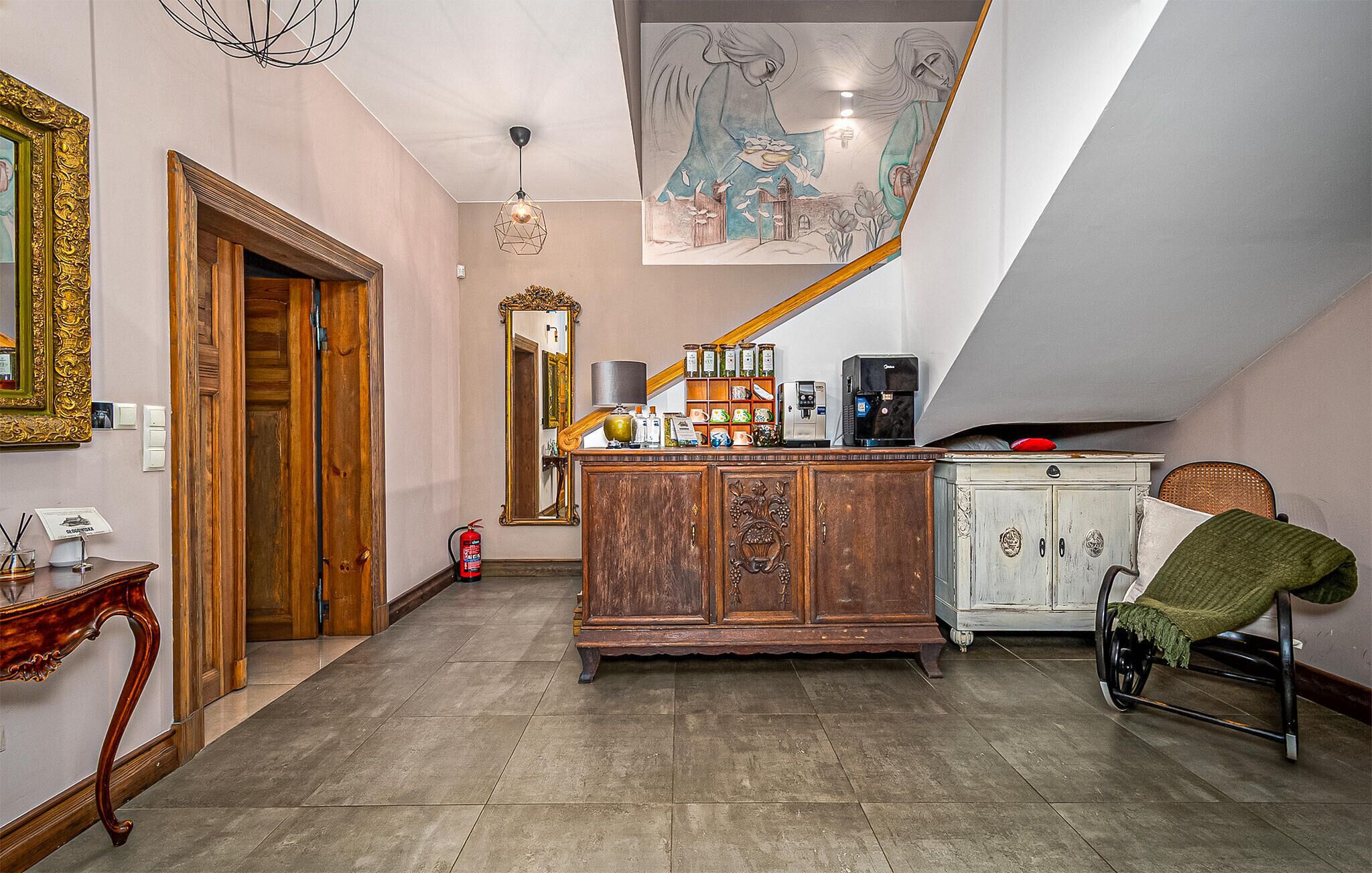 A spacious hallway with a wooden cabinet, a wheelchair, and a staircase leading to an upper level.