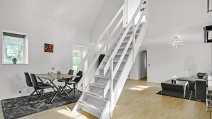 A modern interior with a dining area, a staircase, and a living space.