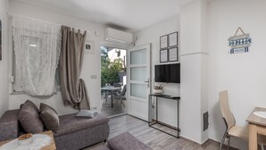 A modern living room with a grey sofa, a small table, and a TV mounted on the wall. - Luxurious home in Crikvenica with WiFi (Crikvenica)