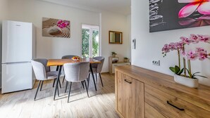 A modern kitchen with a wooden dining table, grey chairs, a white refrigerator, and a cabinet with a mirror.