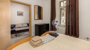 A bedroom with a bed, a bedside table, a mirror, a radiator, a window with curtains, and a view of the outside. - 1 bedroom stunning apartment in Rijeka (Rijeka)