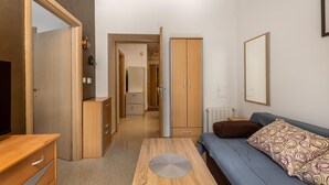 A modern bedroom with a wooden wardrobe, a sofa with patterned cushions, a bedside table, and a large mirror on the wall. - 1 bedroom stunning apartment in Rijeka (Rijeka)