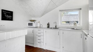 A white kitchen with a microwave, sink, and cabinets. There is a chalkboard with text on the wall. - Amazing home in Thisted with sauna (Thisted)