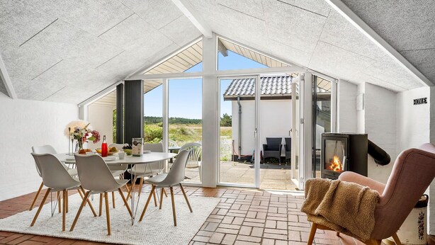 A modern, open-plan living space with a dining area, a fireplace, and a view of the outdoors. - Amazing home in Thisted with sauna (Thisted)