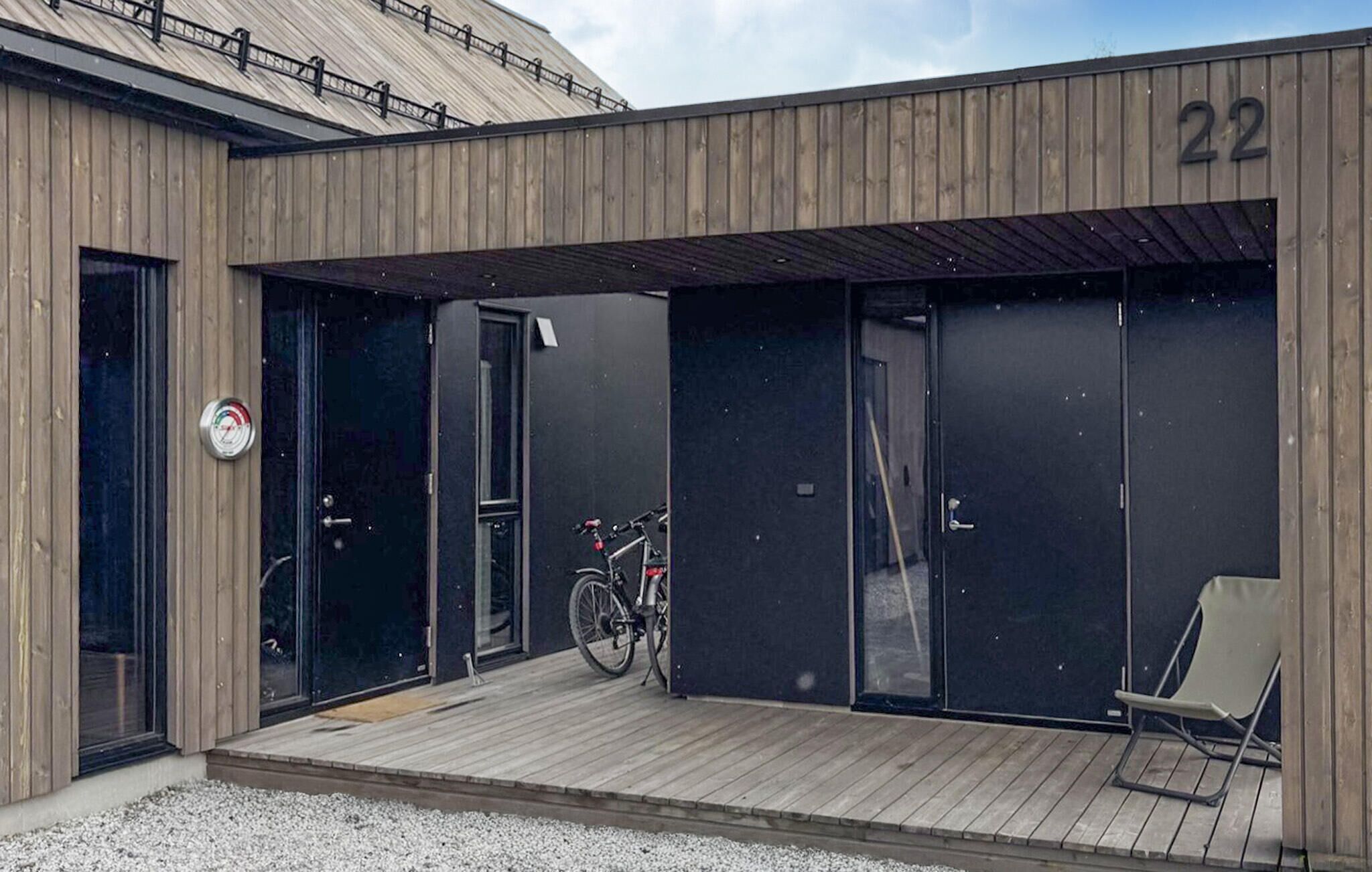 A modern building with a wooden facade, numbered 22, featuring a covered entrance with a bicycle parked inside.