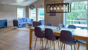 Een modern interieur met een houten vloer, een eettafel met stoelen, een bank en een hanglamp.