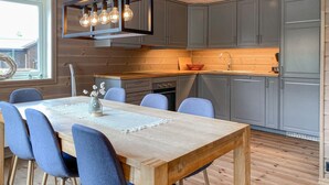 Een moderne keuken met grijze kastjes, een houten eettafel met blauwe stoelen en een hanglamp.