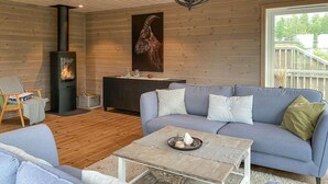 Een gezellige woonkamer met een bank, een bijzettafeltje, een open haard en een groot raam.