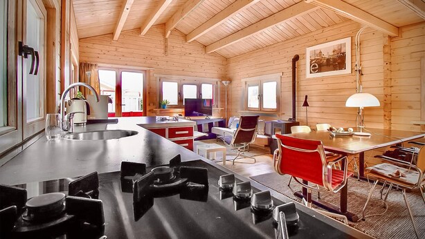 A wooden cabin interior with a kitchen, dining area, and living space.