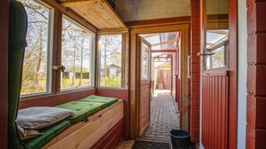 A small, cozy room with a wooden bench and a window overlooking a garden.