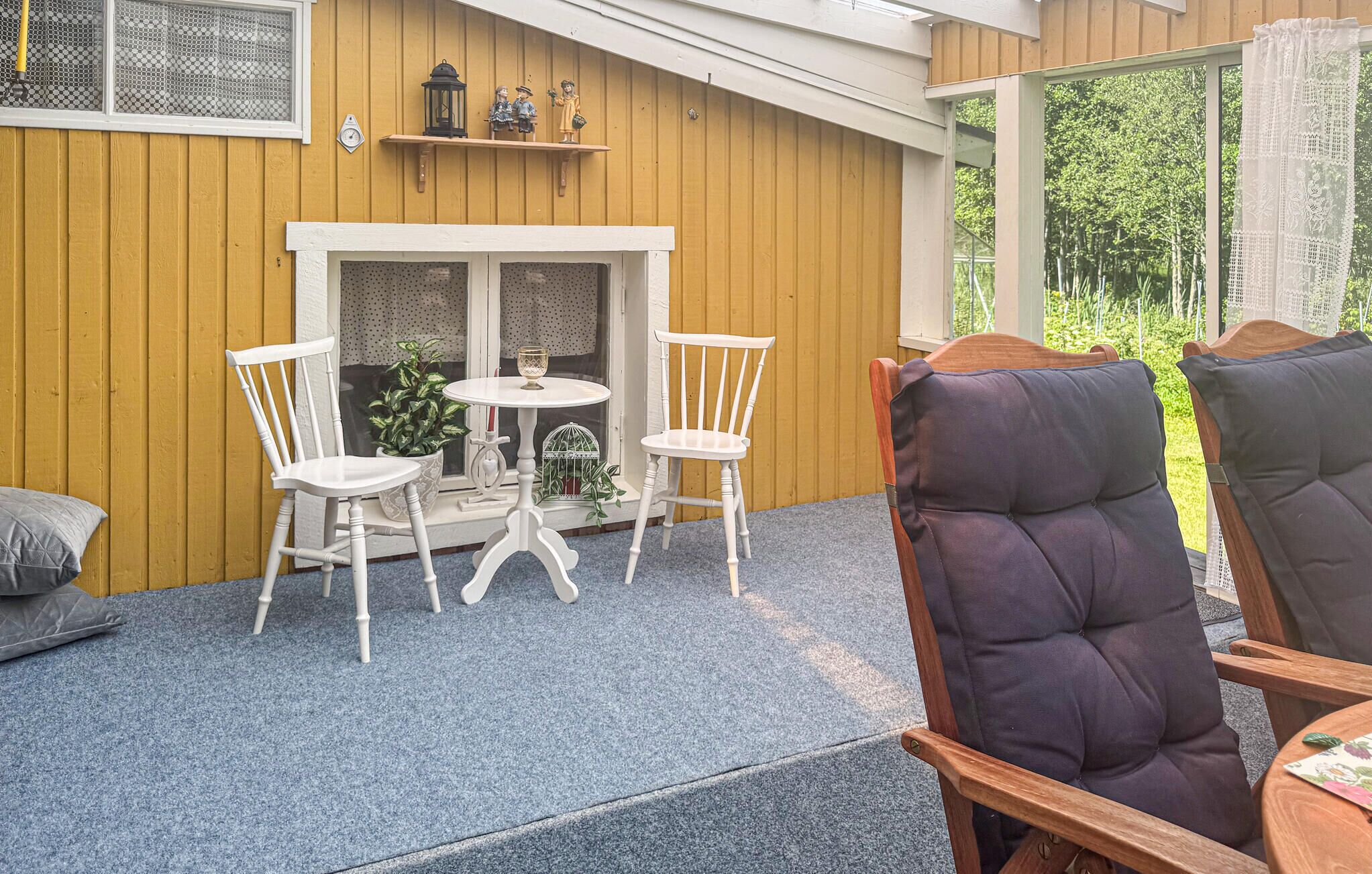 A cozy outdoor seating area with a white table and chairs, a small potted plant, and a decorative lantern on a wooden wall.