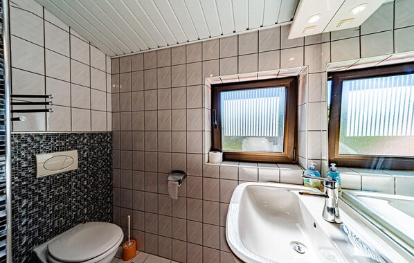 Un baño con inodoro, lavamanos y ventana.