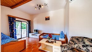 A cozy room with a wooden ceiling, a TV, a small white desk, a sofa with blue pillows, and a patterned armchair. - 1 bedroom pet friendly apartment in Viganj (Viganj)