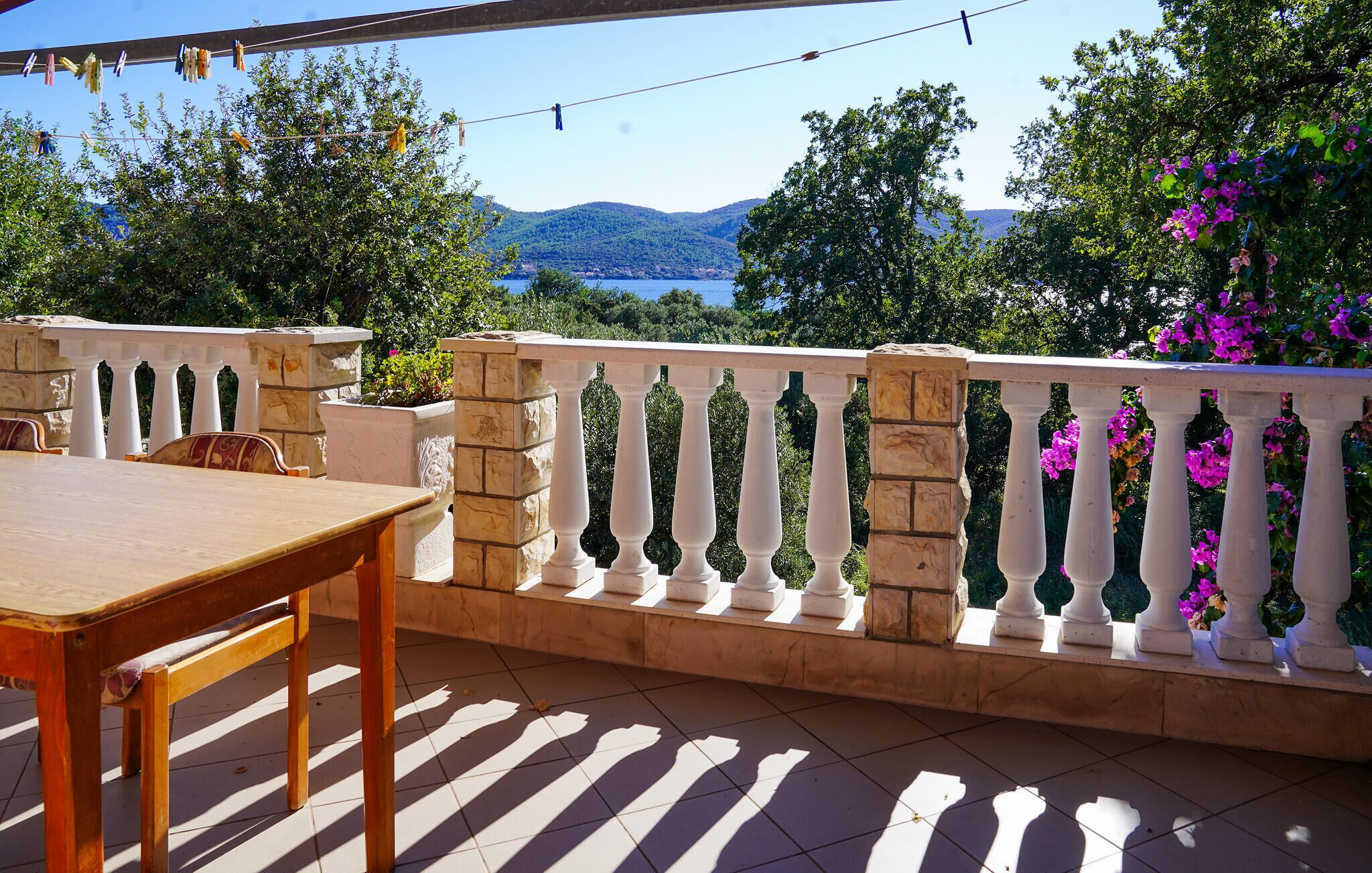 A balcony with a stone balustrade, a wooden table, and chairs.