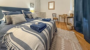 A neatly arranged bedroom with a bed, bedside tables, a chair, and a small table. - Charmante maison de ville (Chantilly)