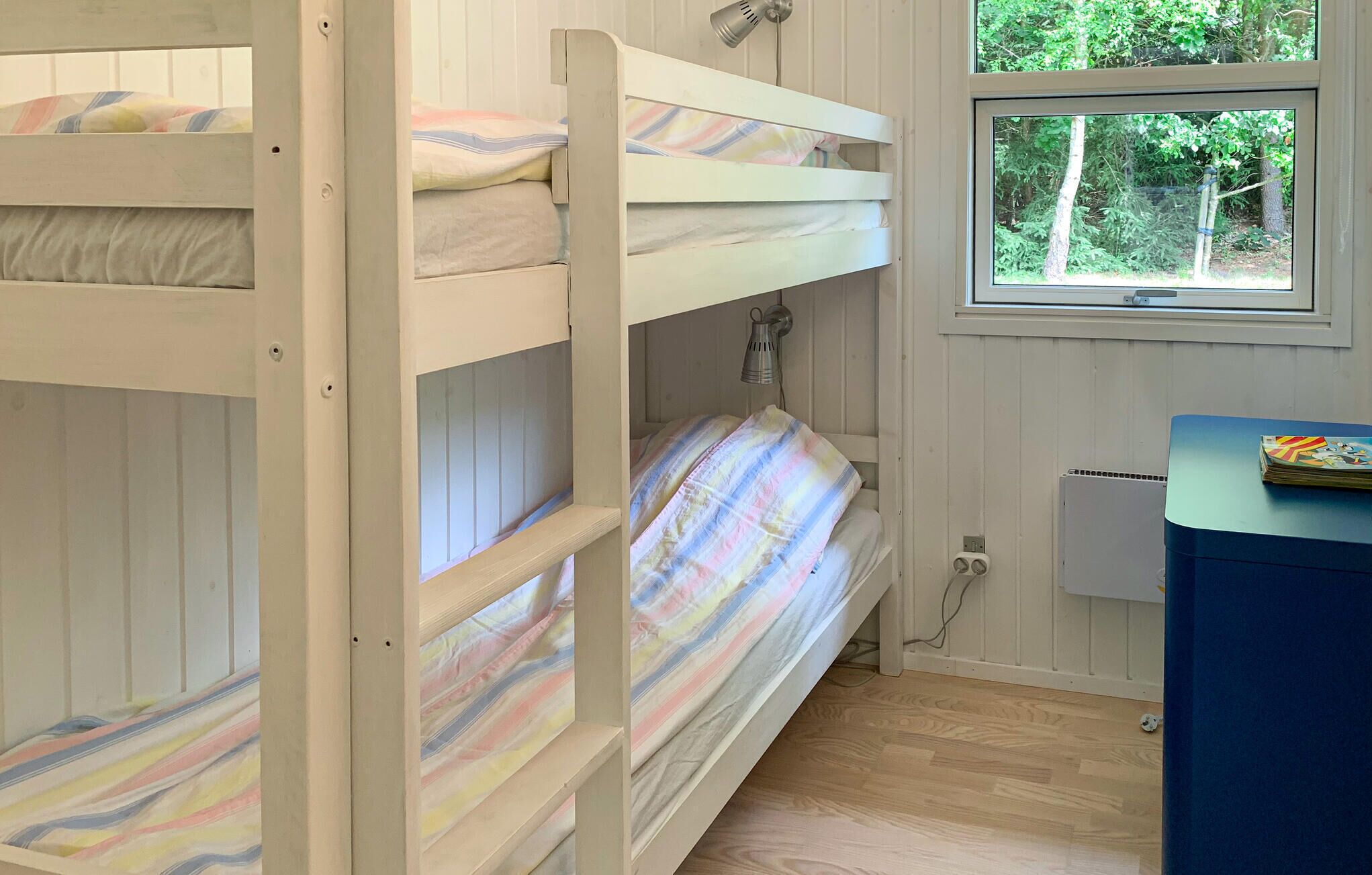A bunk bed room with a window, a desk, and a radiator.