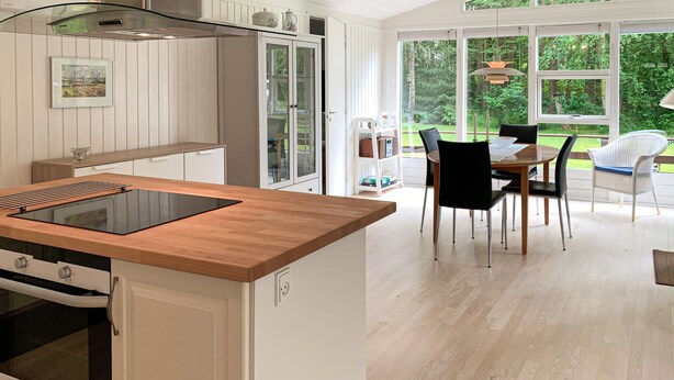 Une cuisine moderne dotée d’un plan de travail en bois, d’un four encastré et d’un coin repas avec une table et des chaises.
