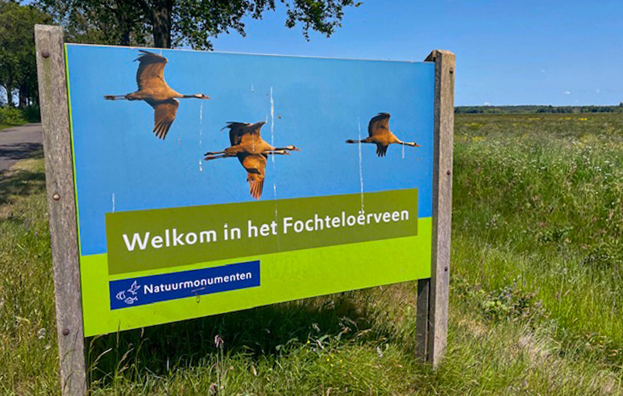 A sign with three birds flying, welcoming visitors to a nature reserve.