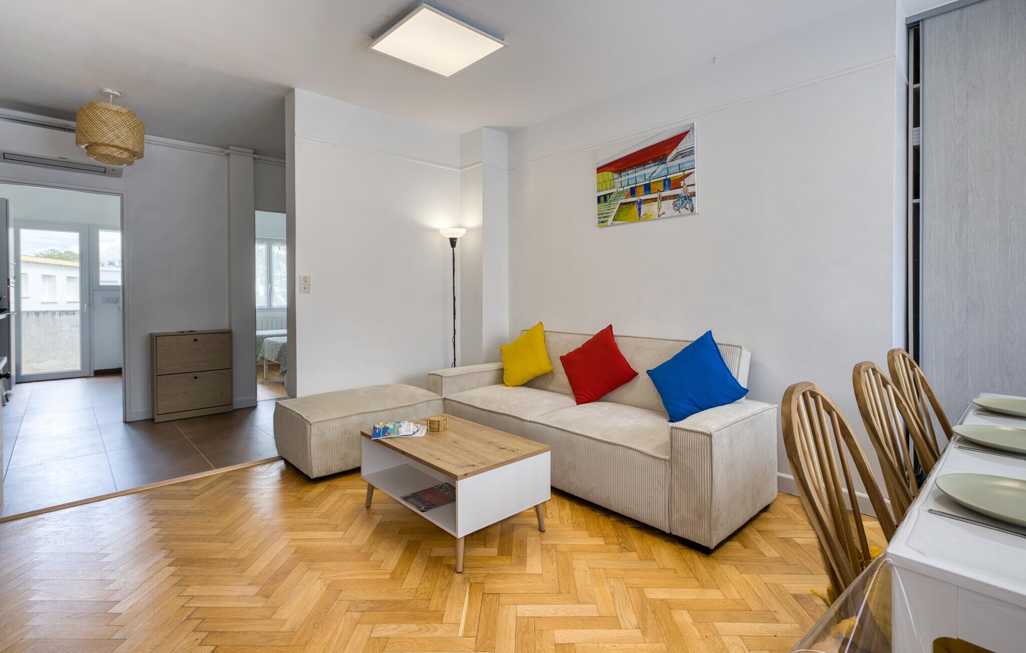 A modern living room with a sofa, a coffee table, and a dining area with chairs and a table.