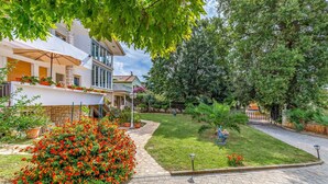 A residential area with a paved driveway, a well-maintained lawn, and a variety of potted plants and flowers. - Lovely apartment in Banjole with WiFi (Banjole)