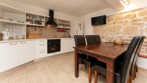 Una cuina moderna amb armaris blancs, forn integrat i zona de menjador amb taula i cadires de fusta.