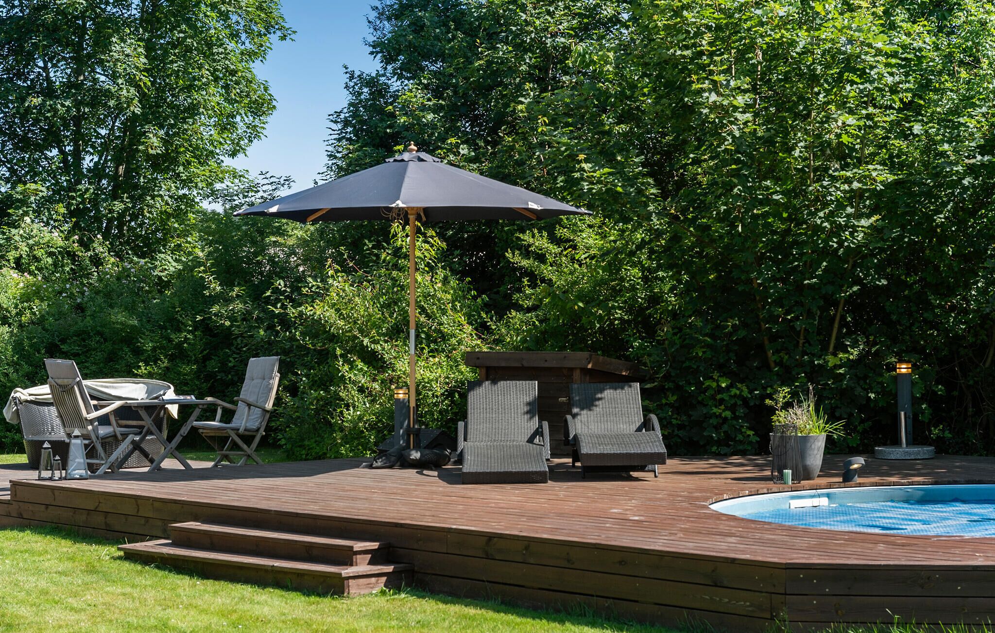 A wooden deck with outdoor furniture, a pool, and a gazebo.