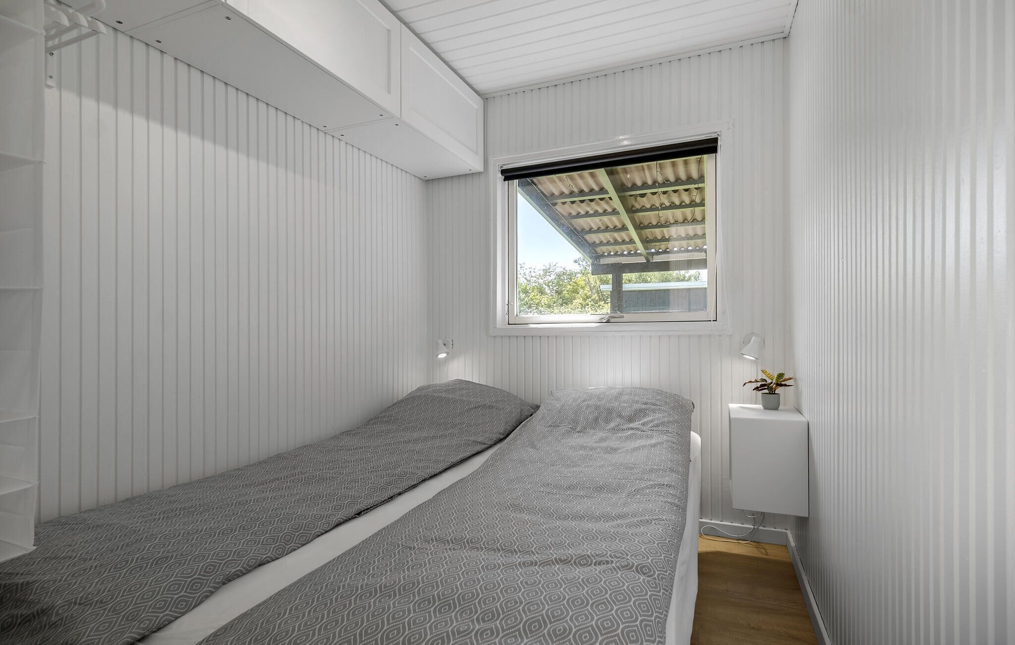 Een kleine kamer met een enkel bed, witte muren en een schuine kap.