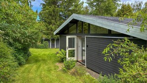 Et moderne hus med mørkt ydre, skråt tag og en velplejet græsplæne.