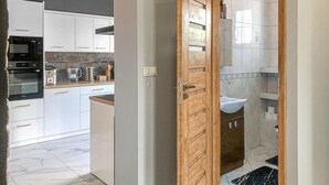 Una cocina moderna con armarios blancos, horno integrado y cafetera.