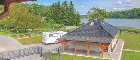 Un terrain de camping pour véhicules récréatifs situé au bord d’un lac, avec un pavillon couvert et un véhicule récréatif blanc.