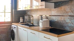 Una cocina moderna con lavadora integrada, hervidor y cafetera sobre la encimera.
