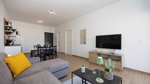 A modern living room with a grey sofa, a coffee table, and a flat-screen TV mounted on the wall. - Lovely apartment in Seget Donji with WiFi (Seget Donji)