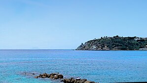 A coastal landscape with a rocky shoreline and a cliff with sparse vegetation.