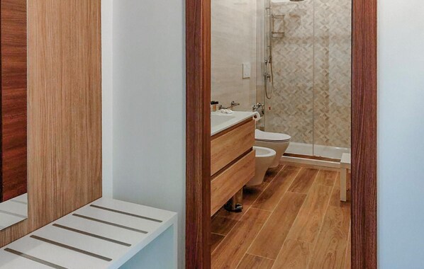 Une salle de bain moderne avec un meuble-lavabo en bois, des toilettes et une douche.