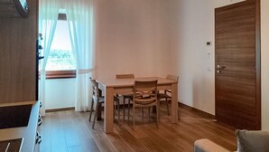 A small, well-lit room with a wooden dining table and four chairs, a wooden door, and a window with sheer curtains. - Pet friendly apartment in Lubriano with sauna (Lubriano)