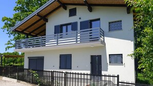 Ein zweistöckiges Gebäude mit Balkon, Garage und schwarzem Zaun.