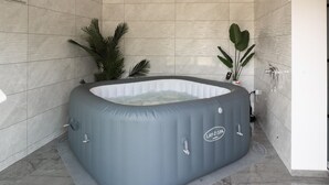 Ein Whirlpool im Badezimmer mit gefliesten Wänden und einem Marmorboden.