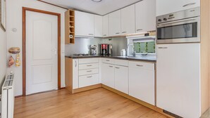 Cozinha moderna com armários brancos, forno embutido e cafeteira.