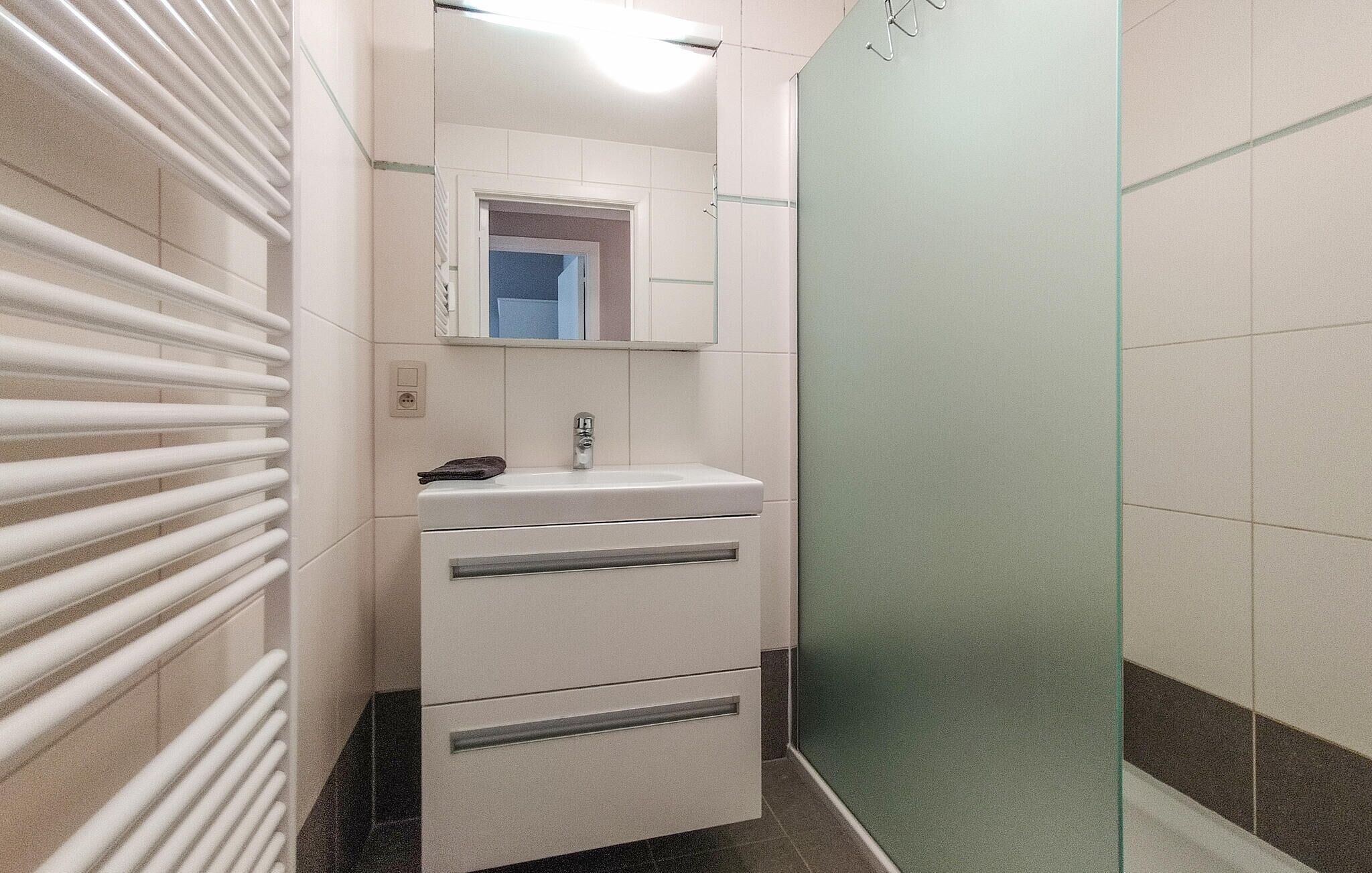 A bathroom with a white sink, mirror, and towel rack.