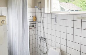 Et badeværelse med bruser, toilet og et vindue.