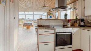 Et moderne køkken med træloft, store vinduer og udsigt til naturen.