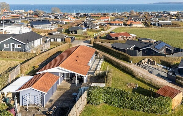 Un barrio residencial con casas, vista despejada al mar y un césped bien cuidado.