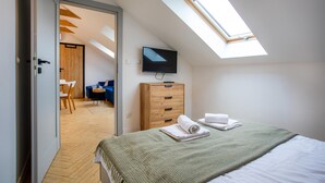 Un dormitorio con tragaluz, televisor montado en la pared, cómoda de madera y cama con toallas.
