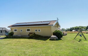 A yellow building with a sloped roof, a bench, and a swing set in the yard. - Nice home in Nordborg with sauna (Nordborg)