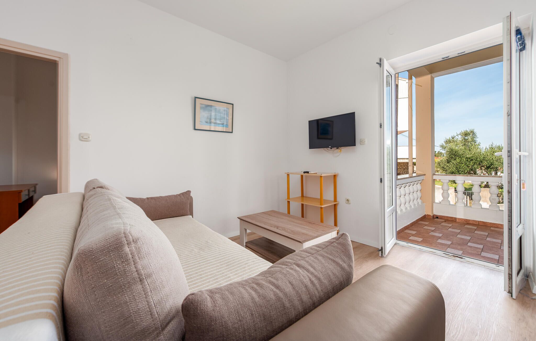 A modern bedroom with a bed, a TV, a small table, and a balcony with a view.