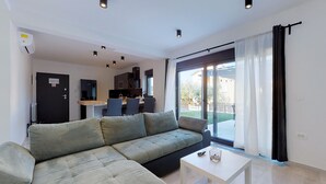A modern living room with a sectional sofa, a dining area, and a sliding glass door leading to a patio. - Awesome apartment in Drenje (Drenje)