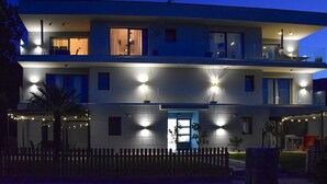A modern two-story building with multiple windows and balconies, illuminated by exterior lighting. - Awesome apartment in Drenje (Drenje)