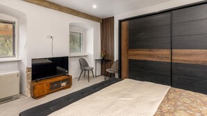 Une chambre à coucher avec un lit, une télévision, une chaise et une porte coulissante.